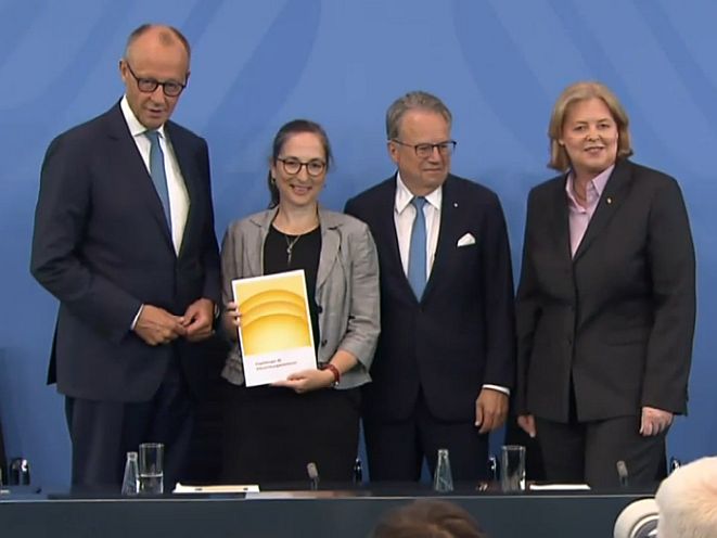 Friedrich Merz, Constanze Janda, Frank-Jürgen Weise und Bärbel Bas im Bundeskanzleramt bei der Vorstellung des Abschlussberichts der Alterssicherungskommission. (Screenshot: VersicherungsJournal)